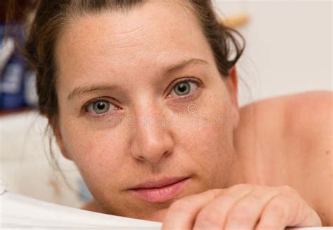 Woman Looks Out Of The Bathtub Her Hand On The Edge Without Make Up