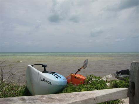 Two Kayaks Sitting On The Beach Next To A Wooden Fence And Body Of Water