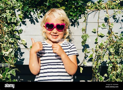 Little Smiling Girl With Wavy Blonde Hair In Heart Shaped Sunglasses