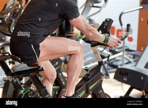 Muscular Man Biking In The Gym Exercising Legs Doing Cardio Workout Cycling Bikes Spinning