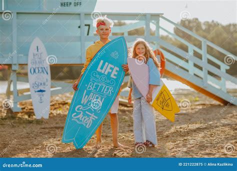 Boy And Girl Posing With Surfboards Against Blue Lifeguard Tower On The