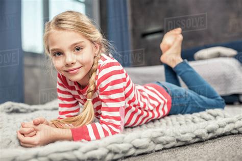 Pretty Little Girl Lying On Floor And Smiling At Camera Stock Photo