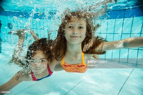 Portrait Of Two Girls Swimming Under Water In Swimming Pool High Res