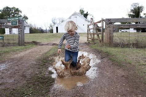 Image Of Young Boy Splashing In Muddy Puddle On The Farm Austockphoto