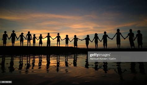 Silhouette Children Holding Hands While Standing Against Sky During