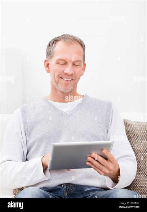 Mature Man Sitting On Couch Using Digital Tablet Stock Photo Alamy