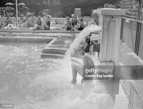 A Girl Cools Down Under The Water Spout At A Private Swimming Pool In