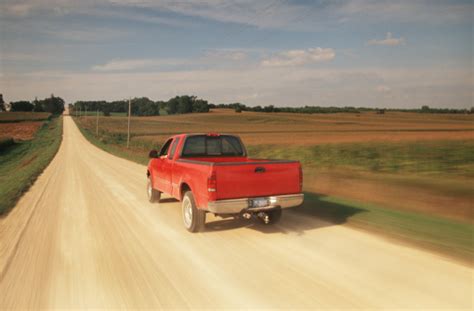 Red Pick Up Truck Traveling Down A Dusty Midwest Road Stock Photo