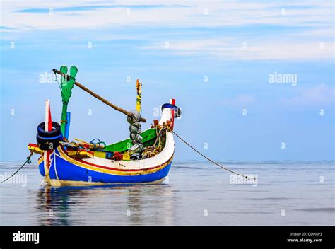 A Traditional Indonesian Fishing Boat Anchored Just Off The Beach Early