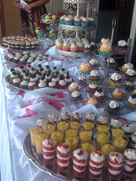 A Table Topped With Lots Of Cupcakes And Desserts Covered In Frosting