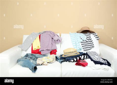 Messy Clothing On White Sofa On Light Wall Background Stock Photo Alamy