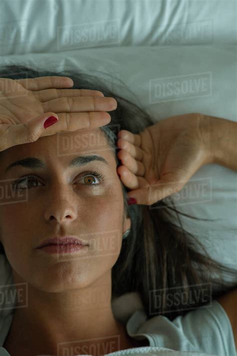 Woman Lying In Bed With Hand On Forehead Stock Photo Dissolve
