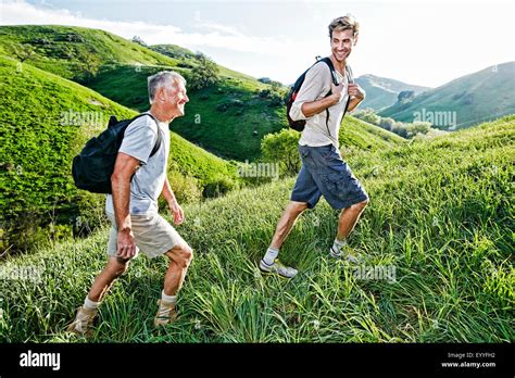 Caucasian Father And Son Walking On Grassy Hillside Stock Photo Alamy
