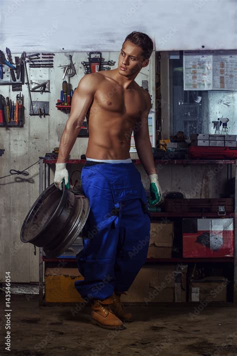 Sexy Auto Mechanic Man Holds A Wheel From The Car In His Hand Stock