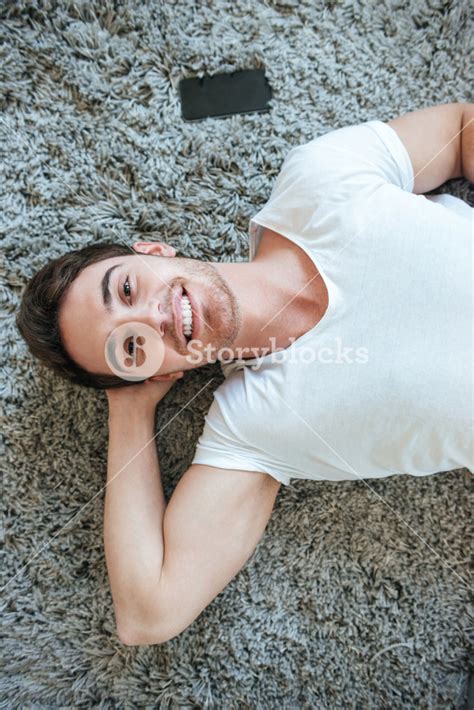 Vertical Image Of Happy Man Lying On The Floor And Looking At Camera