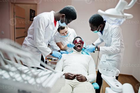Multiracial dentist doctors team. African american man patient at UV