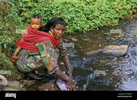 Ethiopia Woman With Baby On Her Back Washing Clothes In A Stream 1998