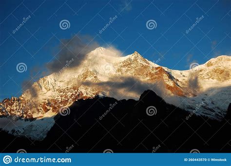 Scenic Shot Of Snowy Mountains Covered With Clouds Under The Sunlight