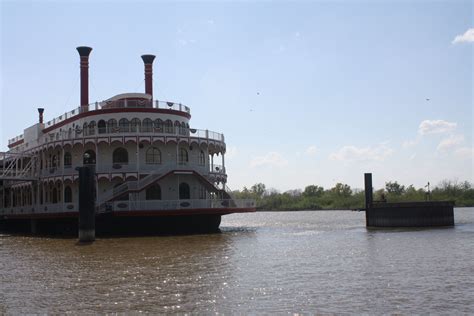 A Large Boat Floating On Top Of A River Next To A Dock With Two Piers