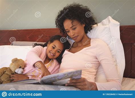 Happy African American Mother And Her Daughter Reading A Book Stock