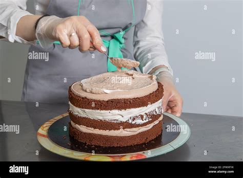 Woman Hands Chef Spreading Cream On Third Layer Of Chocolate Cake Making Chocolate Layer Cake