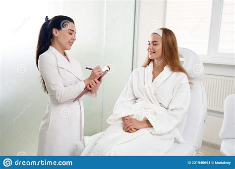 Cosmetologist Consulting Female Patient And Making Notes During Medical