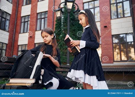 Sitting Together Two Schoolgirls Is Outside Near School Building Stock