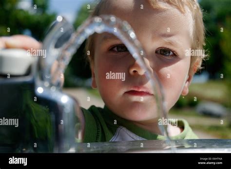 A Young Boy Playing With A Drinking Water Fountain Stock Photo Alamy