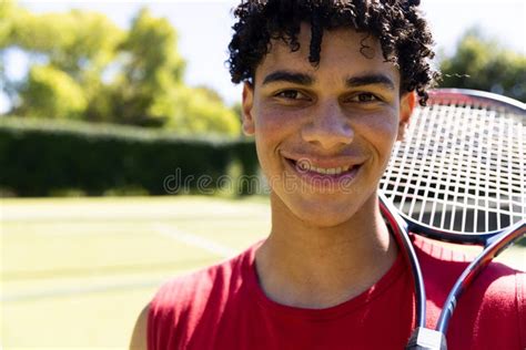 Close Up Of Biracial Young Man With Tennis Racket Smiling In Tennis