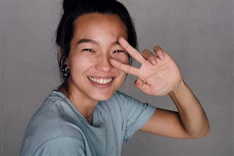 Smiling Asian Girl Showing Peace Sign By Stocksy Contributor Danil