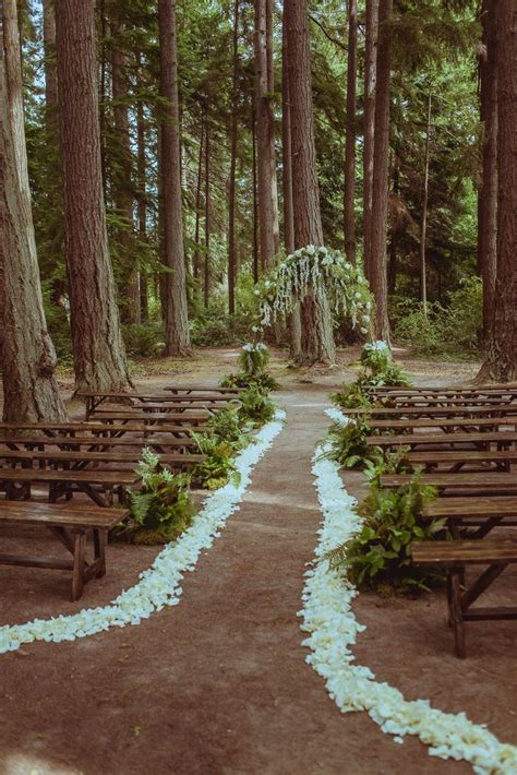 An Outdoor Wedding Ceremony In The Woods With White Flowers And