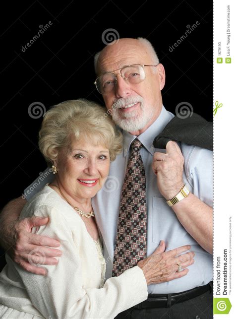 Affectionate Senior Chinese Couple In Front Of House And Sign Stock