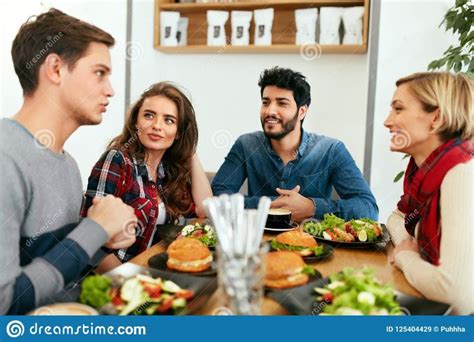 Photo About People Having Dinner Together At Table In Cafe Happy Friends Eating Food At