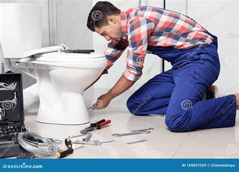 Professional Plumber Working With Toilet Bowl In Bathroom Stock Image
