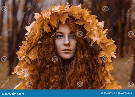 Beautiful Redhead Girl As An Autumn In Leaf Cloak In Forest Background