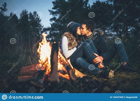 Pretty Couple Relaxing Near Bonfire In The Forest At Evening Tim Stock