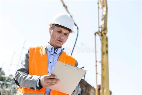 Low Angle View Of Supervisor Writing On Clipboard At Construction Site