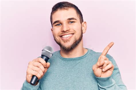 Young Handsome Man Singing Song Using Microphone Smiling Happy Pointing
