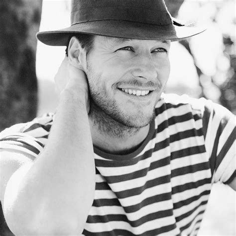 Black And White Photograph Of A Man Wearing A Striped Shirt With A Hat