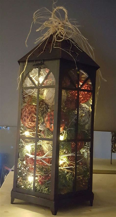 Holiday Greenery Lights And Decorative Ornaments In A Large Lantern