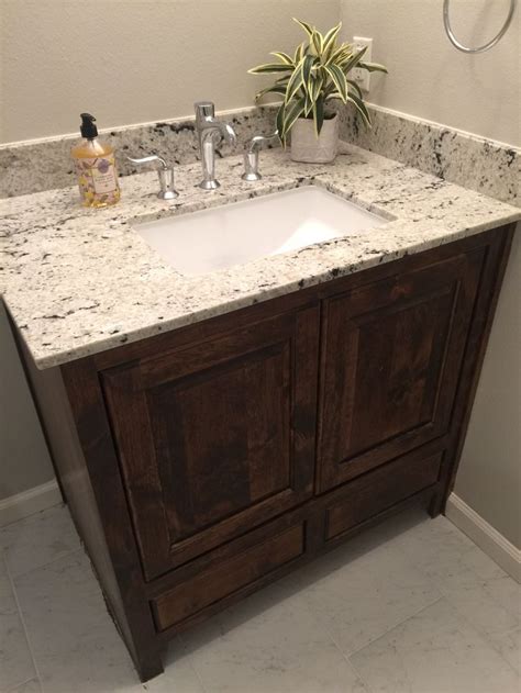A Bathroom Vanity With Marble Counter Top And Wooden Cabinetry In Front