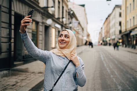 Smiling Young Woman Taking Selfie From Smart Phone While Standing On