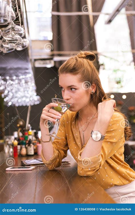Cute Young Girl Drinking Alcohol And Looking At The Barman Stock Photo