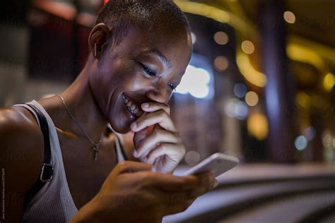 Woman Giggling While Using Her Phone Del Colaborador De Stocksy Jovo