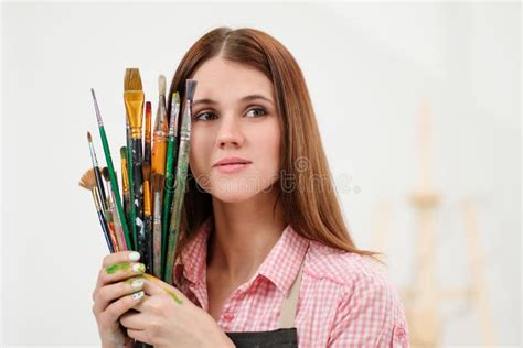Young Woman Artist With Brushes And Paints In A White Studio Stock