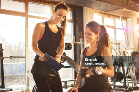 Female Fitness Instructor Showing Exercise Progress On Clipboard To