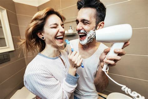 Husband And Wife Sharing Bathroom Together At Home Shaving Beard And Washing Teeth Stock Image