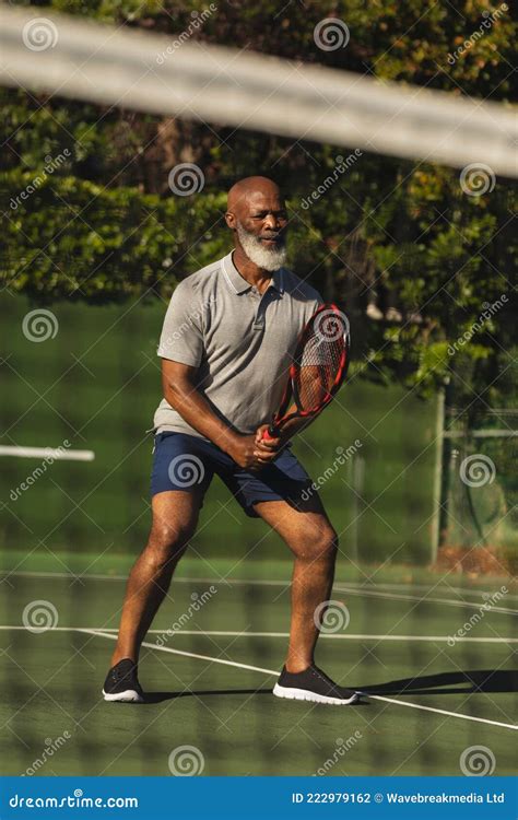 Senior African American Man Playing Tennis On Tennis Court Stock Photo