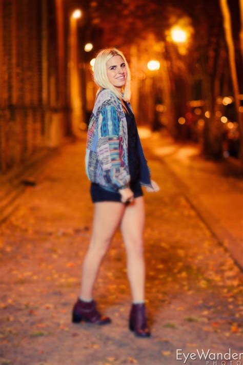 A Woman In Short Shorts And Jacket Posing For The Camera On A Street At