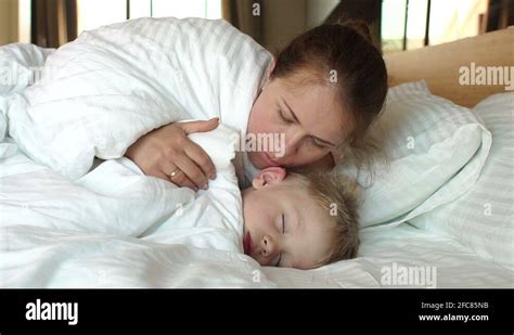 A Caring Mother Wakes Her Sleeping Son In The Morning In Bed Stock